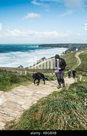 Bedruthan Steps - une marchette et son chien grimper le sentier raide au Bedruthan Steps sur la côte nord des Cornouailles. Banque D'Images