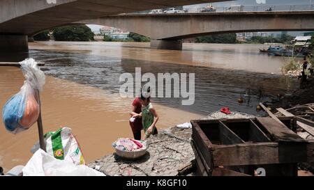 Jeunes filles laver des vêtements sous le pont Monivong Phnom Penh Cambodge la vie le long de la région du fleuve Bassac Vietnam Cambodge Banque D'Images