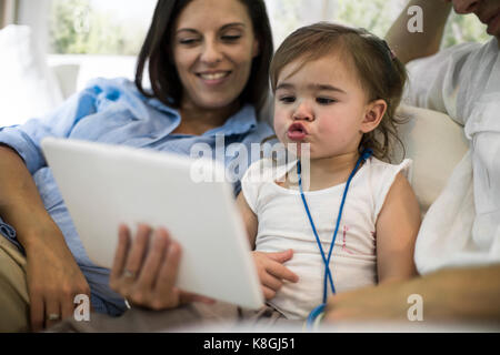 Mari et femme using digital tablet with baby girl on sofa Banque D'Images