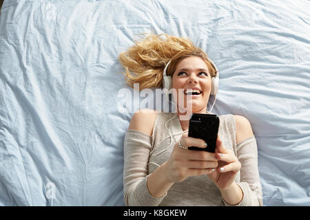 Woman listening to music on bed Banque D'Images