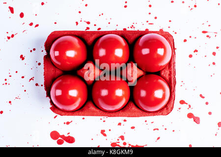 Vue de dessus les oeufs de Pâques peints en rouge en carton avec des éclaboussures sur fond blanc Banque D'Images