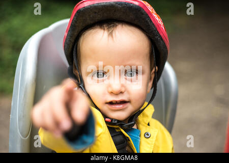 Portrait de jeune garçon assis dans un siège enfant de vélo adultes, faisant Banque D'Images