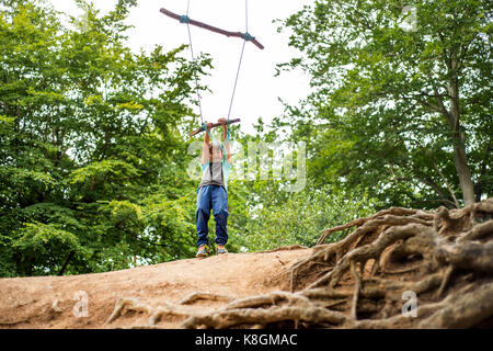 Jeune garçon se balançant sur l'arbre-maison swing Banque D'Images