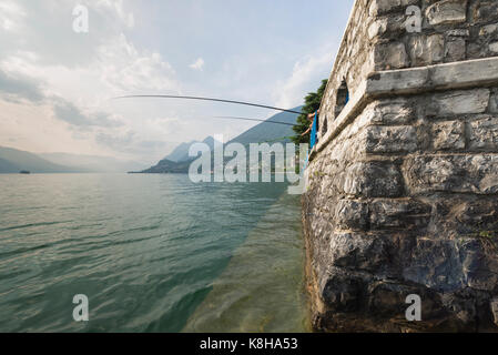 Angler mit langen angelruten an der mauer der seepromenade vente von marasinao am iseosee sale marasino, Lombardie, Italie Banque D'Images