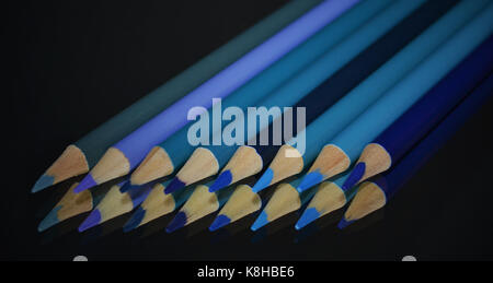 Crayons de couleur bleu sur le miroir d'une réflexion sur un fond noir Banque D'Images