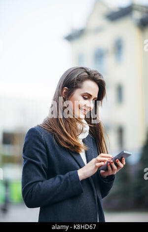 Heureux belle femme sur la rue ville téléphone mobile avec sms écrit Banque D'Images