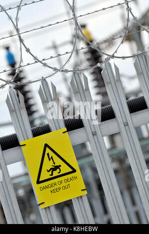 Un conseil d'électricité sous station avec l'escrime palissade et le danger, danger de mort jaune attaché à la clôture comme des avertissements à l'intrus Banque D'Images