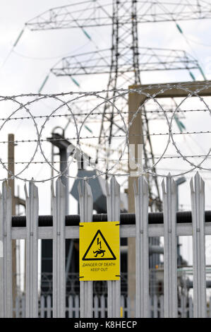 Un conseil d'électricité sous station avec l'escrime palissade et le danger, danger de mort jaune attaché à la clôture comme des avertissements à l'intrus Banque D'Images