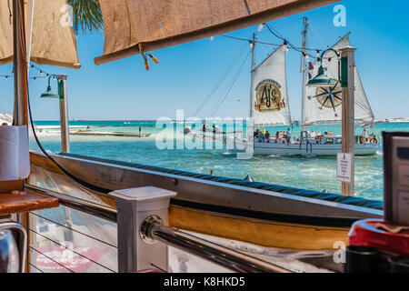 Vue du col avec un voilier de passage, en Floride, du Destin T Harry's restaurant, au port de plaisance de loisirs Harborwalk. Banque D'Images