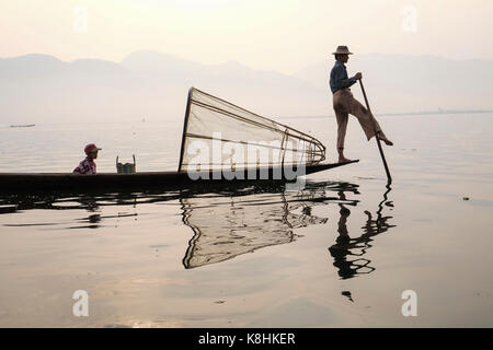 La Birmanie, Myanmar : pêcheur sur une barge sur le lac Inle. Pêcheur avec son fils sur une barge et un piège à poisson en forme de cône Banque D'Images