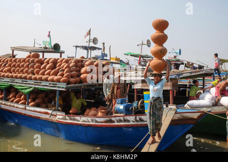 La Birmanie, Myanmar, Mandalay : déchargement des pièces de poterie sur le quai de la rivière Irrawaddy. Femme portant sur sa tête en faïence Banque D'Images