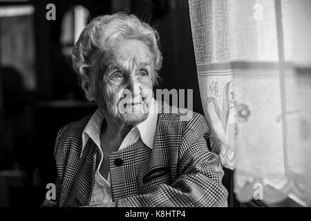 Portrait de stern vieilles femmes, en noir et blanc près de la fenêtre. Banque D'Images