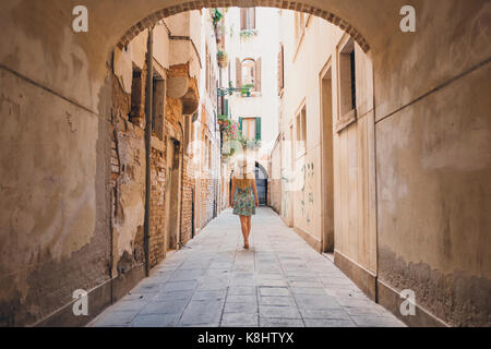 Vue arrière de la femme marchant dans un sentier étroit au milieu de bâtiments Banque D'Images