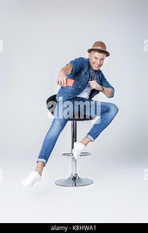 Bel homme en denim est assis sur une chaise Banque D'Images