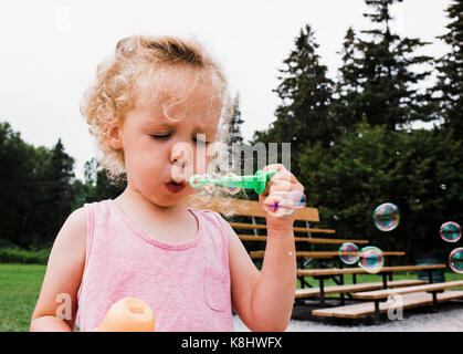 Cute girl blowing bubbles à jeux pour enfants Banque D'Images