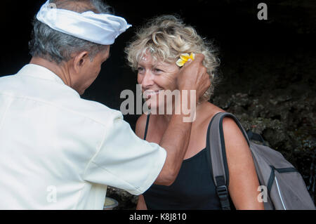 L'Indonésie. bali. Nusa Tenggara. kabupaten de Tabanan, Pura Tanah lot temple hindou. Construit sur un îlot. Un touriste est béni par un prêtre hindou Banque D'Images