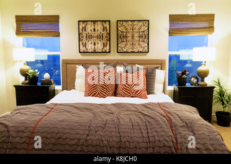 Rouge et gris d'une grande chambre de maître avec des tables de nuit et lampes. Banque D'Images