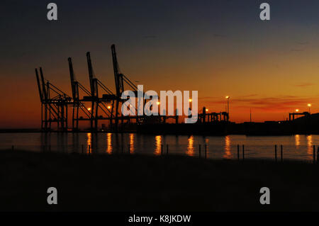 Rangée de grues du port de Malaga au coucher du soleil se reflétant dans l'eau de mer Banque D'Images