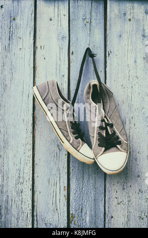 Vieux mâle bleu sneakers accrocher sur un clou sur un mur en bois bleu, vintage toning Banque D'Images