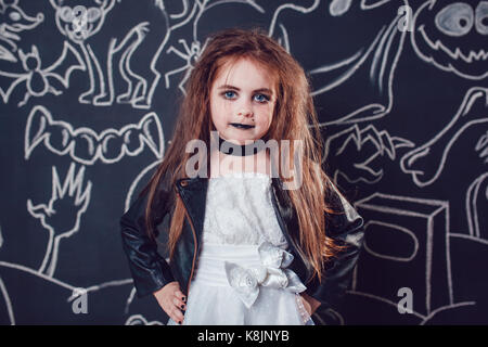 Fille dans bride of chucky doll costume sur fond sombre avec des illustrations d'halloween. Banque D'Images