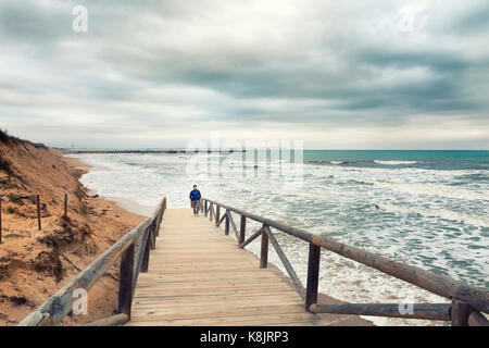 Homme marchant sur la demande dans un jour de tempête et embrouillé dans la mer méditerranée. Guardamar del segura, alicante espagne. Banque D'Images