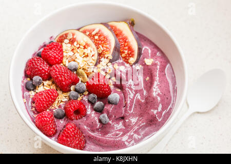 Bol à smoothie (bleuet, l'açaï) aux figues, framboises et granola vegan. petit-déjeuner sain concept. Banque D'Images