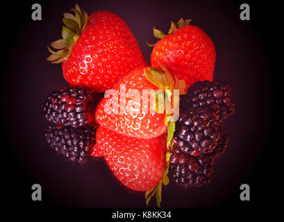 Arrangement des fraises et les mûres avec miroir sur fond violet/noir Banque D'Images