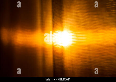 Le ciel d'orange et d'un disque floue du soleil, photographié à travers la matière. photo close-up - coucher de temps de prise de vue. Banque D'Images