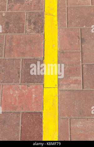 Ligne de marquage jaune sur la route faite de carreaux sombres. photo close up Banque D'Images