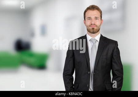 Portrait of young businessman standing in office blanc moderne. Banque D'Images