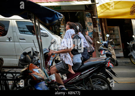 Femme portant un enfant dans ses bras tout en motocyclette. La Thaïlande Asie du sud-est Banque D'Images