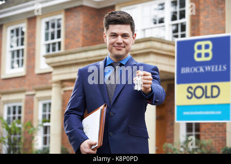 Homme debout à l'extérieur de la propriété de l'agent immobilier résidentiel holding keys Banque D'Images