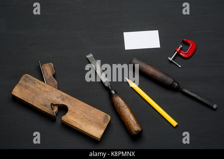 Outils de menuiserie en bois sombre sur fond de table avec blank business card Banque D'Images