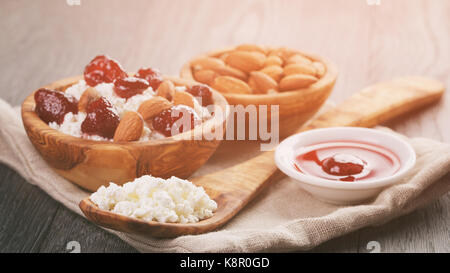 Le fromage cottage avec préservés de la fraise au bol en bois sur table en chêne Banque D'Images