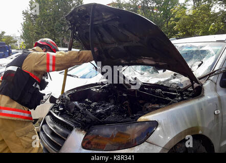 Officier pompier qui enquête sur la voiture brûlée. Banque D'Images