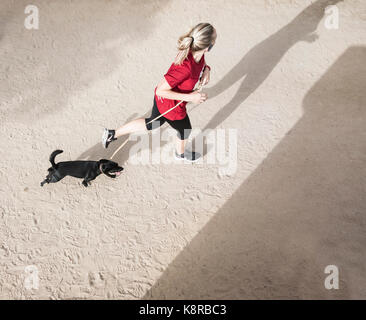 Jeune femme jogging avec chiens. Banque D'Images