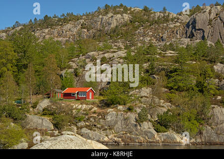 En bois peint rouge maisons de vacances de style norvégien traditionnel sur les pentes des montagnes rocheuses avec des arbres Banque D'Images