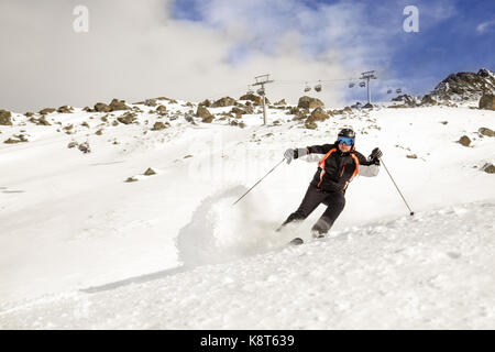 Skieur dans une haute montagne et en faisant glisser les nuages de neige poudreuse dans l'hiver ski resort avec bleu ciel nuageux sur l'arrière-plan. L'Autriche, la région de ischgl Banque D'Images