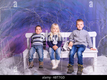 Trois enfants assis sur un banc en hiver. Banque D'Images