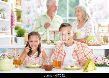 Frère et soeur de prendre le petit déjeuner avec leurs parents sur l'arrière-plan Banque D'Images