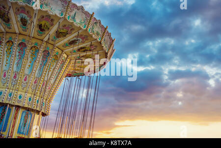 Wave swinger ride against blue sky, vintage des effets de filtre - pas de rotation carousel ride juste au crépuscule Banque D'Images