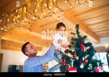 Jeune père avec daugter decorating Christmas Tree ensemble. Banque D'Images