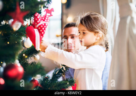 Jeune père avec daugter decorating Christmas Tree ensemble. Banque D'Images