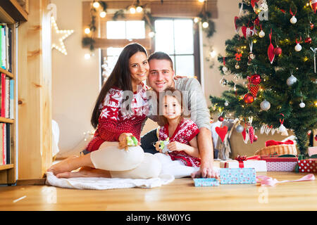 Jeune famille avec daugter à arbre de Noël à la maison. Banque D'Images