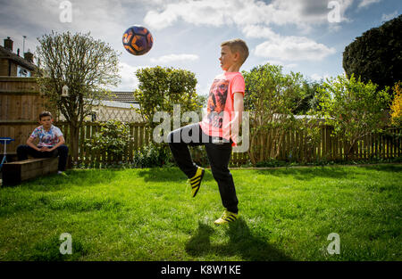 Garçon jouant au football à la maison Banque D'Images