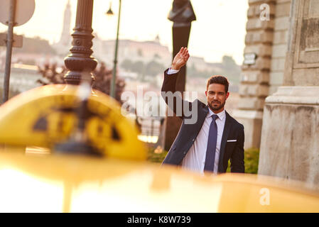 Un beau jeune businessman waving pour un taxi Banque D'Images