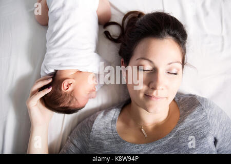 Happy mother and baby lying on bed at home Banque D'Images