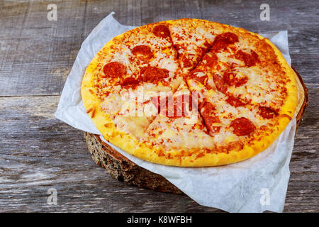 Tasty crispy tortilla au four à pizza au pepperoni, avec saucisses italiennes épicées, de fromage fondu avec une seule tranche d'être servi dans un restaurant, Close up Banque D'Images