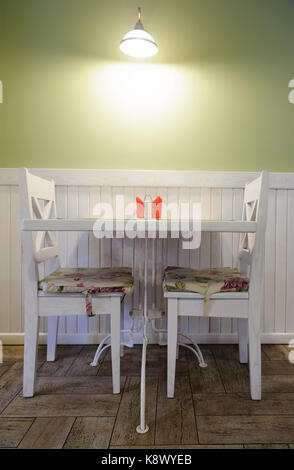 Table pour deux dans un café chaleureux avec des murs vert pastel Banque D'Images