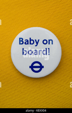 Un bébé à bord d'un insigne porté sur un vêtement en tissu jaune (usage éditorial uniquement). Banque D'Images